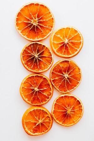 Bright circular dried orange slices are neatly arranged in a line on a light background showcasing their vibrant color and texture.の写真素材