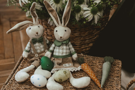 Festive bunnies sit among colorful Easter eggs and carrots arranged in a woven basket for spring decor.の写真素材