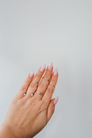 A well groomed hand displays multiple stylish rings and neatly manicured nails on a neutral background.の写真素材