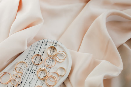 Rings and earrings are beautifully arranged on a simple plate atop soft flowing fabric radiating elegance and charm.の写真素材
