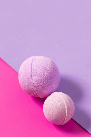 Two bath bombs in pastel colors rest on a smooth background with vibrant pink and purple sections adding a fun touch to relaxation.の写真素材