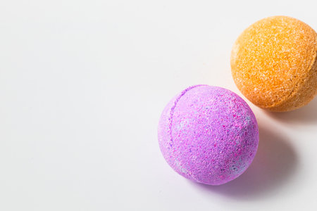 Colorful bath bombs in purple and orange are placed on a white surface ready to be used for a relaxing bath experience.の写真素材