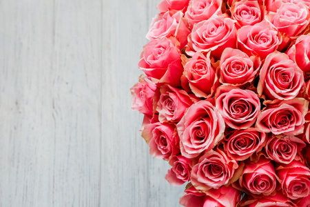 A vibrant bouquet of pink roses showcases delicate petals placed artfully on a rustic wooden background perfect for celebrations.の写真素材