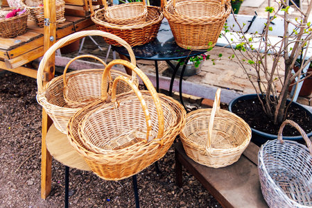 Colorful woven baskets of various sizes rest on wooden tables at an outdoor market during a sunny spring day showcasing artisanal craftsmanship.の写真素材
