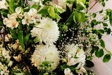 A vibrant assortment of white chrysanthemums and delicate greenery fills a bright indoor area...