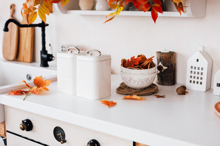 A kitchen counter adorned with autumn leaves decorative containers and a bowl of natural elements creates a cozy seasonal atmosphere.の写真素材