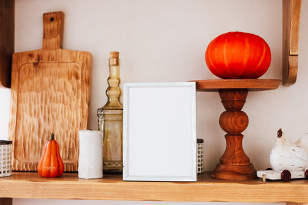 A decorative shelf displays a variety of autumn themed items including pumpkins bottles and a blank frame arranged harmoniously.の写真素材