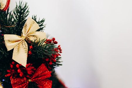 A beautifully adorned Christmas tree features a golden bow lush green branches and vibrant red...