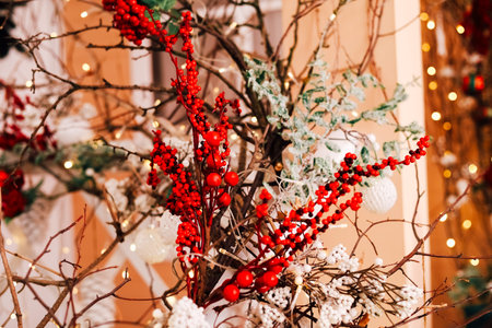 Bright red berries and lush greenery are beautifully arranged in a festive indoor environment decorated for the holiday season.の写真素材