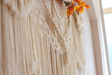 Intricate macrame wall hanging features detailed knots and fringes adorned with colorful autumn...