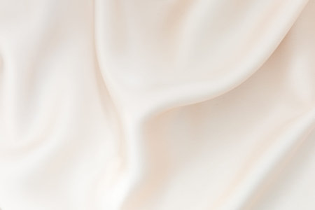 The cream fabric is elegantly draped showing its smooth texture and gentle folds. Natural light...