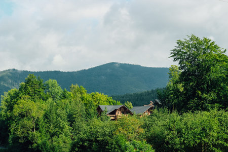 A wooden cabin is surrounded by tall trees and green bushes creating a peaceful retreat in the heart...