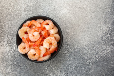 The bowl is filled with plump cooked shrimp that have a light pink hue. They are neatly arranged and ready to be enjoyed during a satisfying dinner.の写真素材