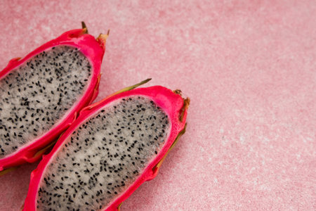 Brightly colored dragon fruit is cut in half displaying its unique texture and contrast of pink and white. This tropical fruit is popular for its taste and health benefits.の写真素材