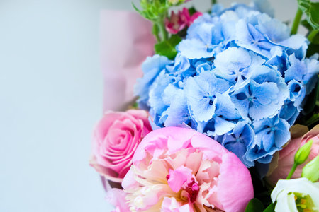 A vibrant bouquet features delicate blue hydrangeas and soft pink roses perfectly arranged for a celebration. The fresh flowers display a range of colors adding beauty and joy to any setting.の写真素材