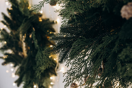 Lush evergreen branches create a festive atmosphere indoors adorned with warm twinkling lights. The scene evokes a cozy inviting feeling perfect for winter celebrations and gatherings.の写真素材