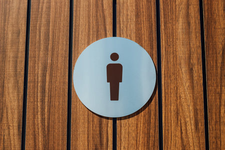 Restroom sign placed on a wooden panel wall clearly indicates the location for men. This design...