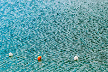 Brightly colored buoys drift on the surface of tranquil water. The gentle ripples create a soothing...