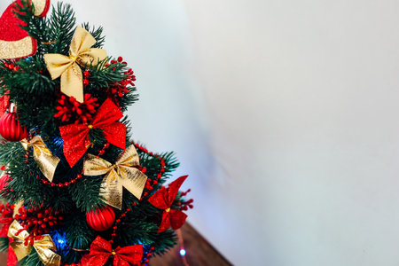 A vibrant Christmas tree stands adorned with red and gold bows ornaments and lights.の写真素材