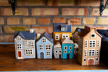 Ceramic houses in various colors sit neatly on a wooden shelf. The houses display charming details...