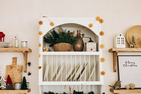 A charming kitchen shelf displays a mix of decorative items like dried oranges green plants and rustic ceramics. The overall setup creates a warm and welcoming holiday vibe in the room.の写真素材