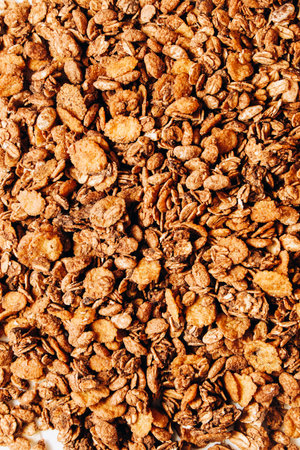 Granola sits in a scattered pile showcasing oats nuts and honey coating. Ideal for a nutritious breakfast or snack. Perfectly baked to a crunchy texture it offers a delicious flavor.の写真素材