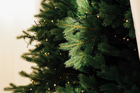 The vibrant pine tree adorned with warm lights creates a cozy atmosphere for winter festivities. Its lush green branches invite joy and togetherness perfect for holiday cheer.の写真素材