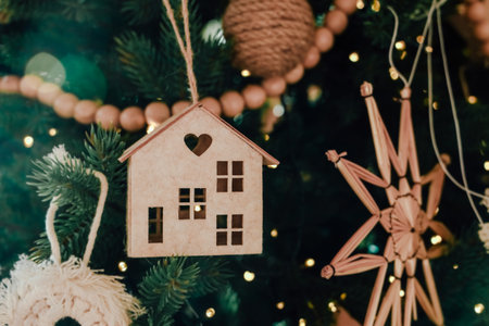A beautifully crafted ornament in the shape of a house hangs from a Christmas tree.の写真素材