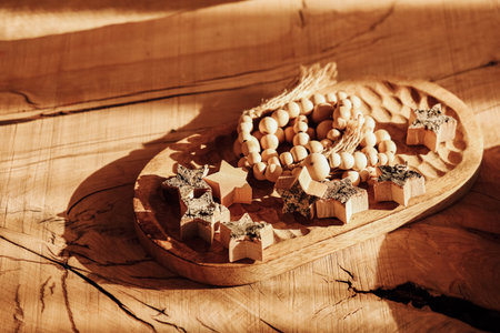 A collection of handcrafted wooden stars and beads rests on a textured wooden surface. The warm light accentuates the natural grain and beauty of the wood creating an inviting scene.の写真素材