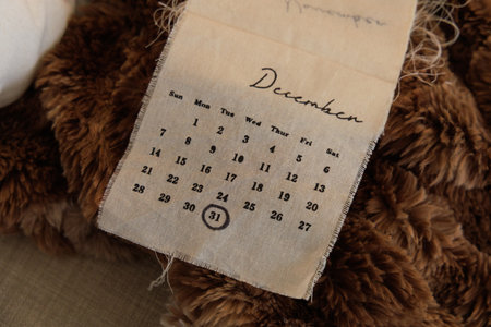 A calendar page from December displays the days of the week and numbered dates. The page is made of fabric showing a rustic and vintage style that enhances its visual appeal.の写真素材