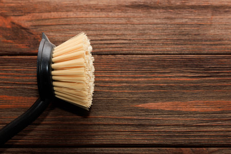 Cleaning brush rests on a rustic wooden table highlighting the bristles and handle. The warm tones of the wood add a cozy feel to the scene perfect for home cleaning tasks.の写真素材