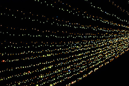 Colorful lights stretch across the dark sky, creating a pattern that adds excitement to the festive atmosphere. People gather below to enjoy the display at the city event.