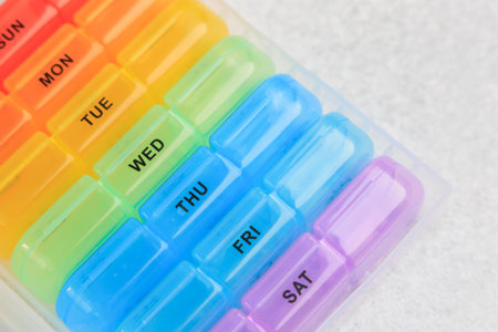 The weekly pill organizer is displayed with compartments labeled for each day. It is arranged from Sunday to Saturday. The colors are bright and easy to see.