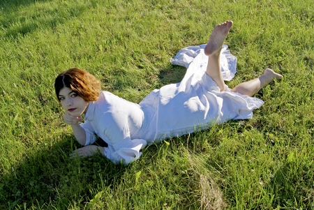 girl in a white dress lies on a grassの写真素材