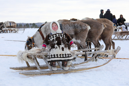 NADYM, RUSSIA  MARCH 04, 2018: Nenets girl in national dress sitting on a sled during the holiday of the reindeer breeder Day. Nenets  aboriginals of the Russian Northのeditorial素材