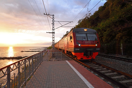 Sochi, RUSSIA - AUGUST 13, 2013: Commuter train arrives at sunset on the Black seaのeditorial素材