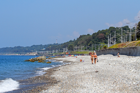 Sochi, RUSSIA-AUGUST 10, 2013: a couple in love walks along a pebble beach on the Black sea coastのeditorial素材