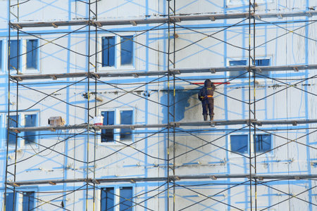 Nadym, Russia-FEBRUARY 28, 2015: an Installer prepares the facade of a high-rise panel house for...