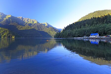 Gudauta district, ABKHAZIA-AUGUST 08, 2013: Tourists ride a catamaran on lake Ritsa in the evening among the Caucasus mountainsのeditorial素材