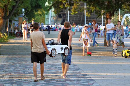 Krasnodar, Russia-AUGUST 16, 2015: Young people carry a children's car for rent in an amusement Park in the city square on Krasnaya streetのeditorial素材