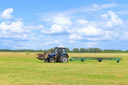 Altai, Russia-JULY 28, 2015: a machine Operator on the MTZ-80 tractor Belarus is engaged in harvesting hay for livestock farms in the Altai territoryのeditorial素材