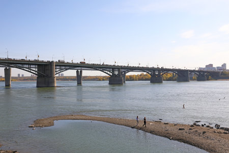 Novosibirsk, RUSSIA - girls walk on the Bank of the Ob river against the background of the Oktyabrsky bridgの写真素材