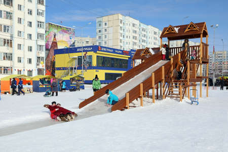 Nadym, RUSSIA-MARCH 14, 2021: Children have fun and ride down the slide on a sunny frosty day during the Maslenitsa holidayのeditorial素材