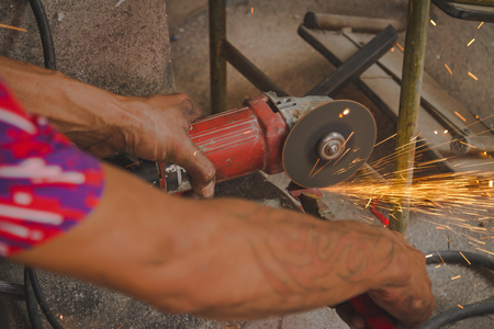 Craftsman sawing metal sparkles all around workshopの写真素材