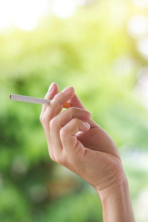 Women's hand carries cigarettes Green tree backgroundの写真素材