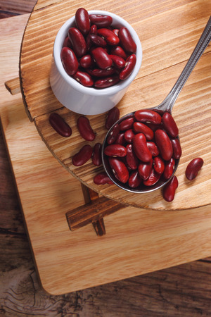 Red beans on a silver spoon placed on a small wooden tableの写真素材