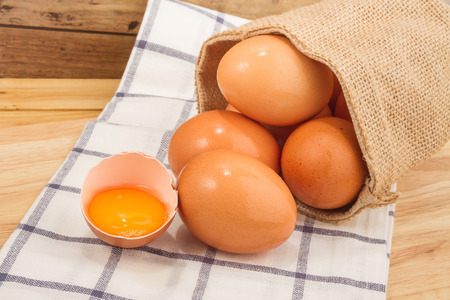 Brown egg in a small sack on a beautiful cloth background on a wooden tableの写真素材
