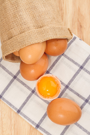 Brown egg in a small sack on a beautiful cloth background on a wooden tableの写真素材