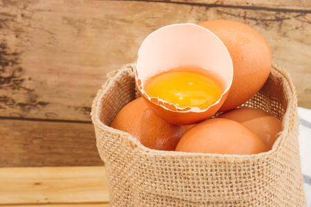 Brown egg in a small sack on a beautiful cloth background on a wooden tableの写真素材