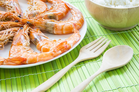 Roast shrimps seafood on white dish and wooden kitchenware with selective focusの写真素材
